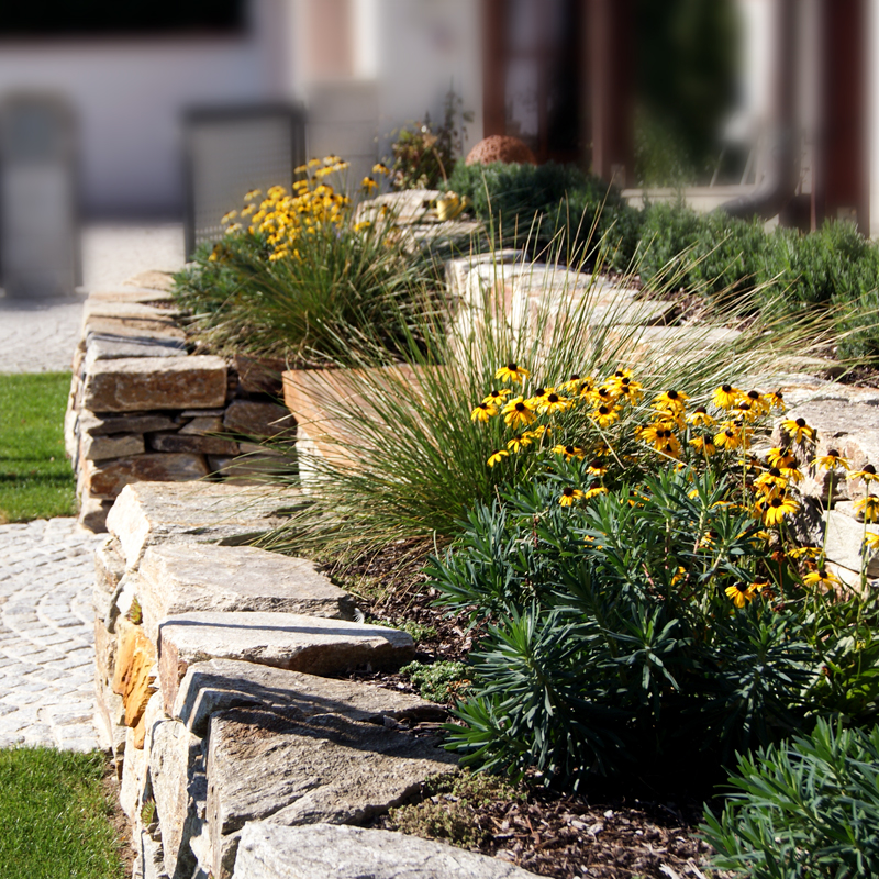 Gartengestaltung Eder Steinmauer Blumenbeet aus Natursteinen mit dekorativer Bepflanzung